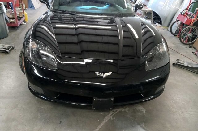 A black corvette is parked in the garage.