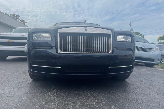 A black rolls royce parked in a lot.