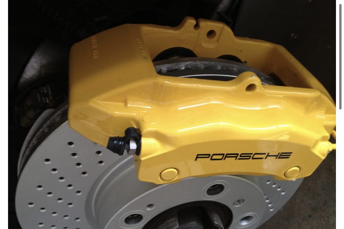 A yellow brake caliper and disc are on the ground.